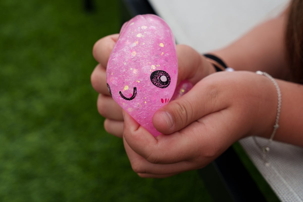 A child's hand squeezing a pink glittery squishy dumpling toy
