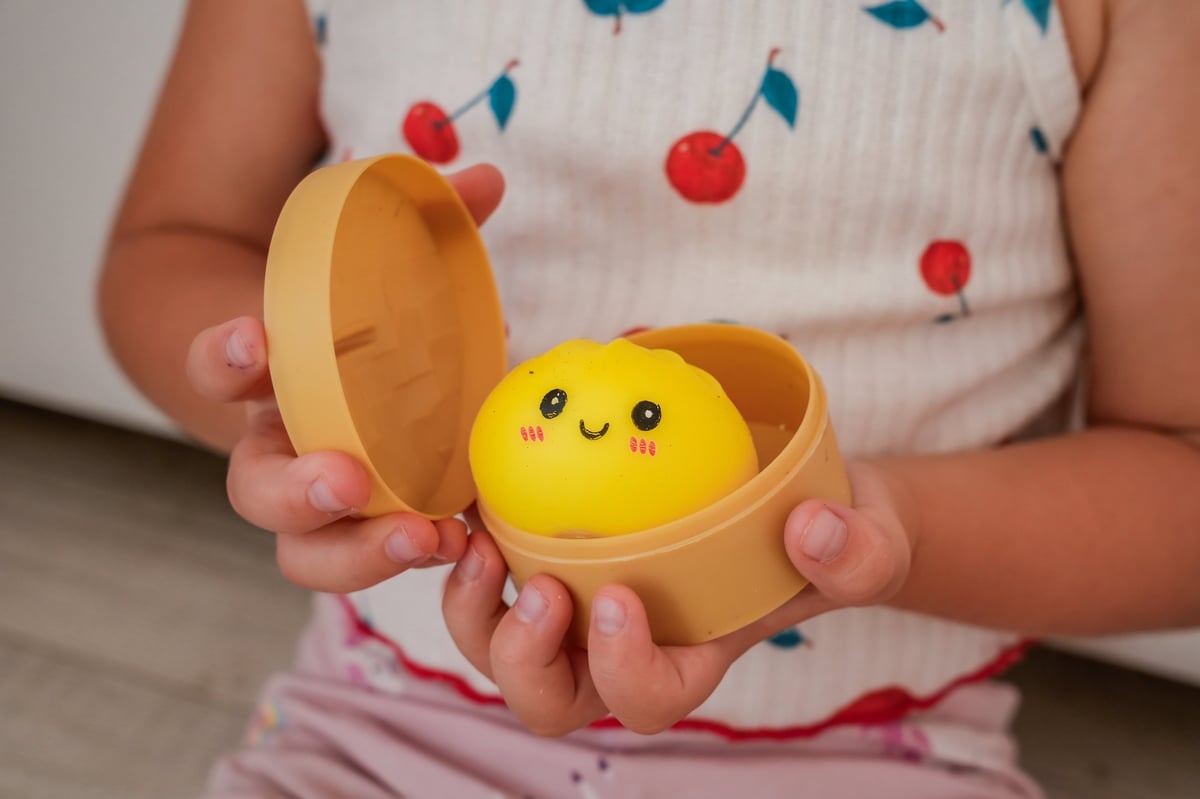 Child holding a bamboo steamer filled with dumpling squishy toys